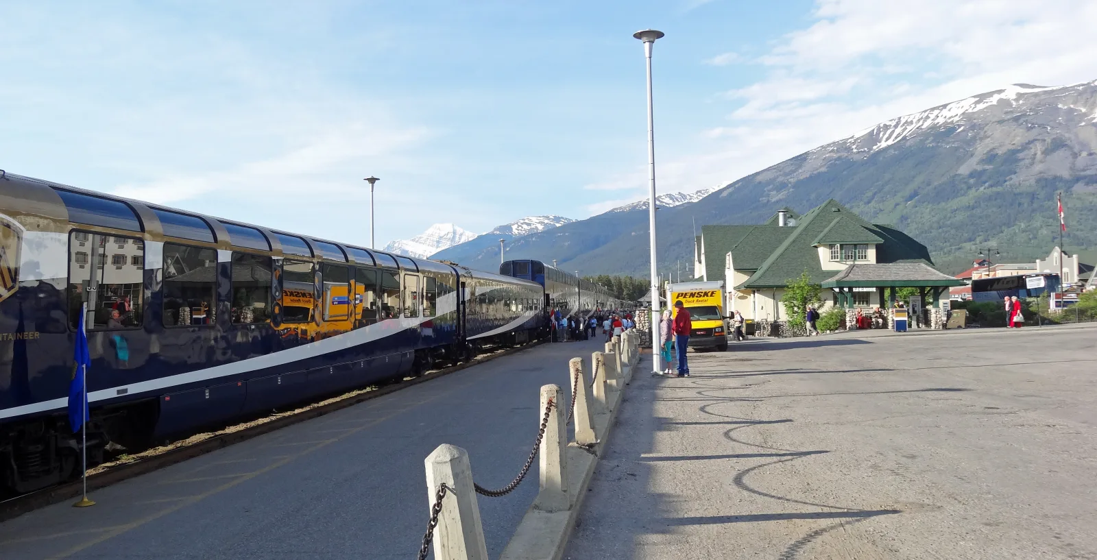 A Rocky Mountaineer train standing at Jasper station beneath the Canadian Rockies