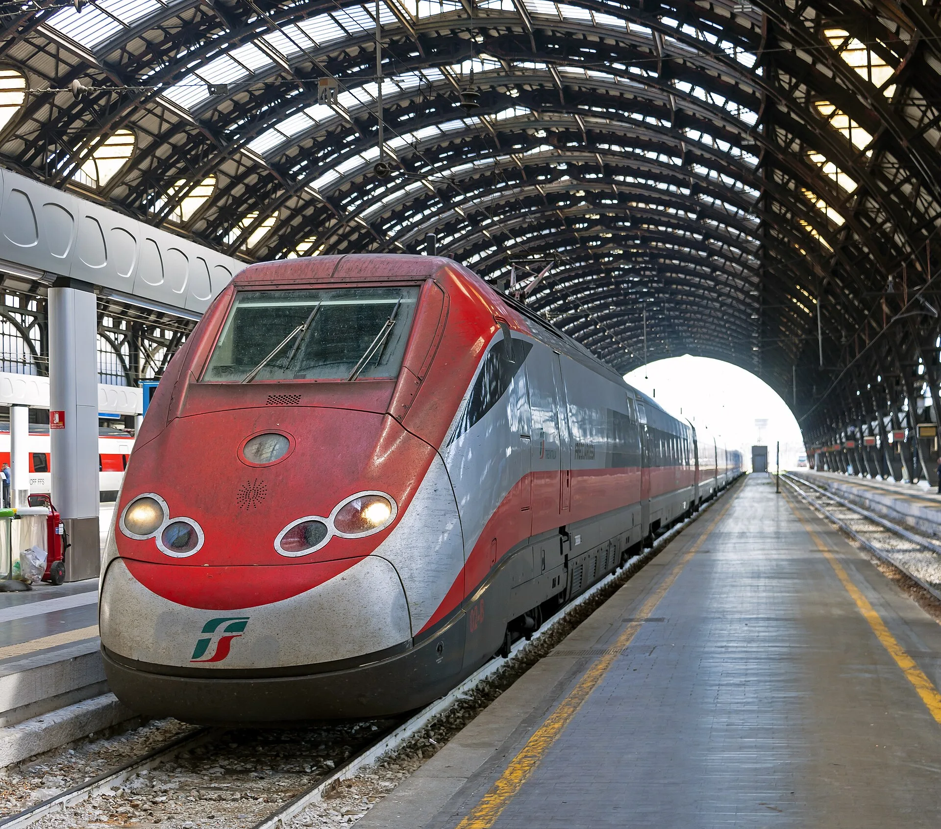 A red high-speed train at an Italian railway station
