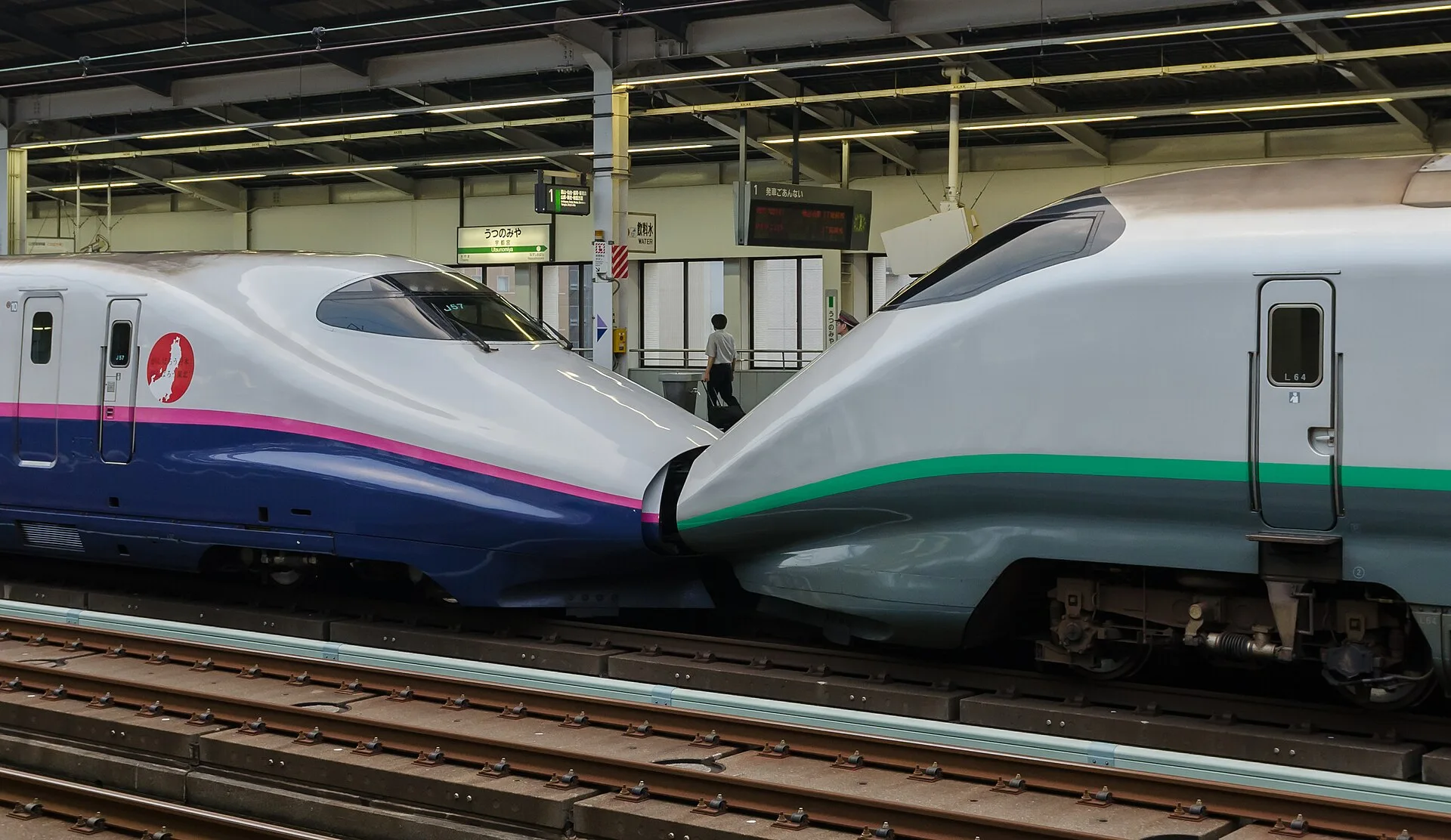 Two Shinkansen trains meeting at a station platform in Japan
